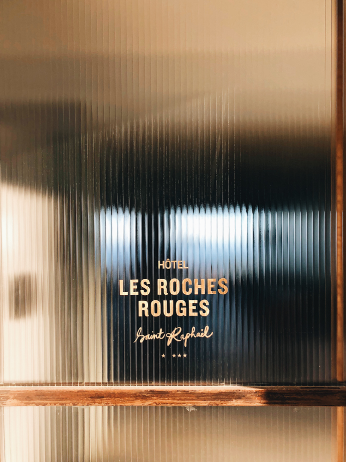Les Roches Rouges While the chic entrance to the hotel is on a main beach thoroughfare, it is subtly shielded from road traffic by thick, translucent sliding glass doors imprinted with the hotel logo.