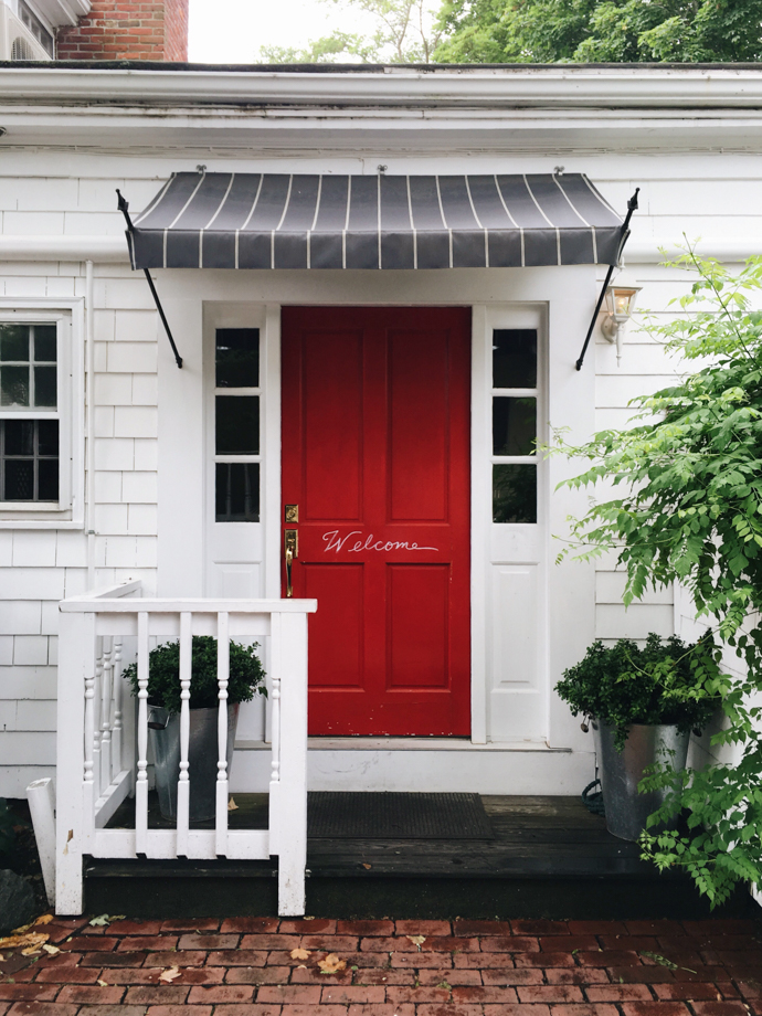 Eben House The quaint side entrance to the hotel features a bright red door with a hand-painted welcome sign.