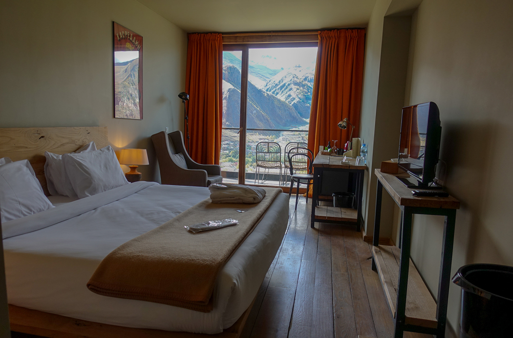 Rooms Hotel Kazbegi Great choices for a lean room: heavenly bed, balcony facing the mountains, and warm hardwood floors.