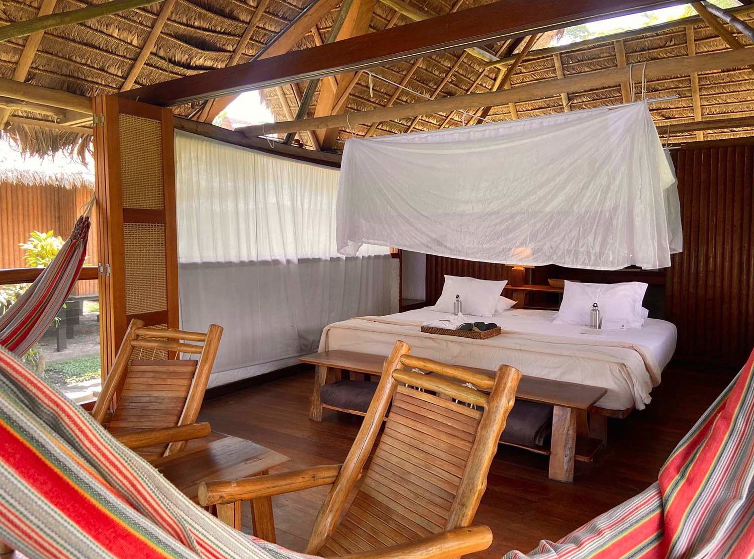 Inkaterra Reserva Amazonica High thatched roof wooden cabanas with king bed (or twin beds) with canopy mosquito net, 100% cotton sheets and hypoallergenic pillows