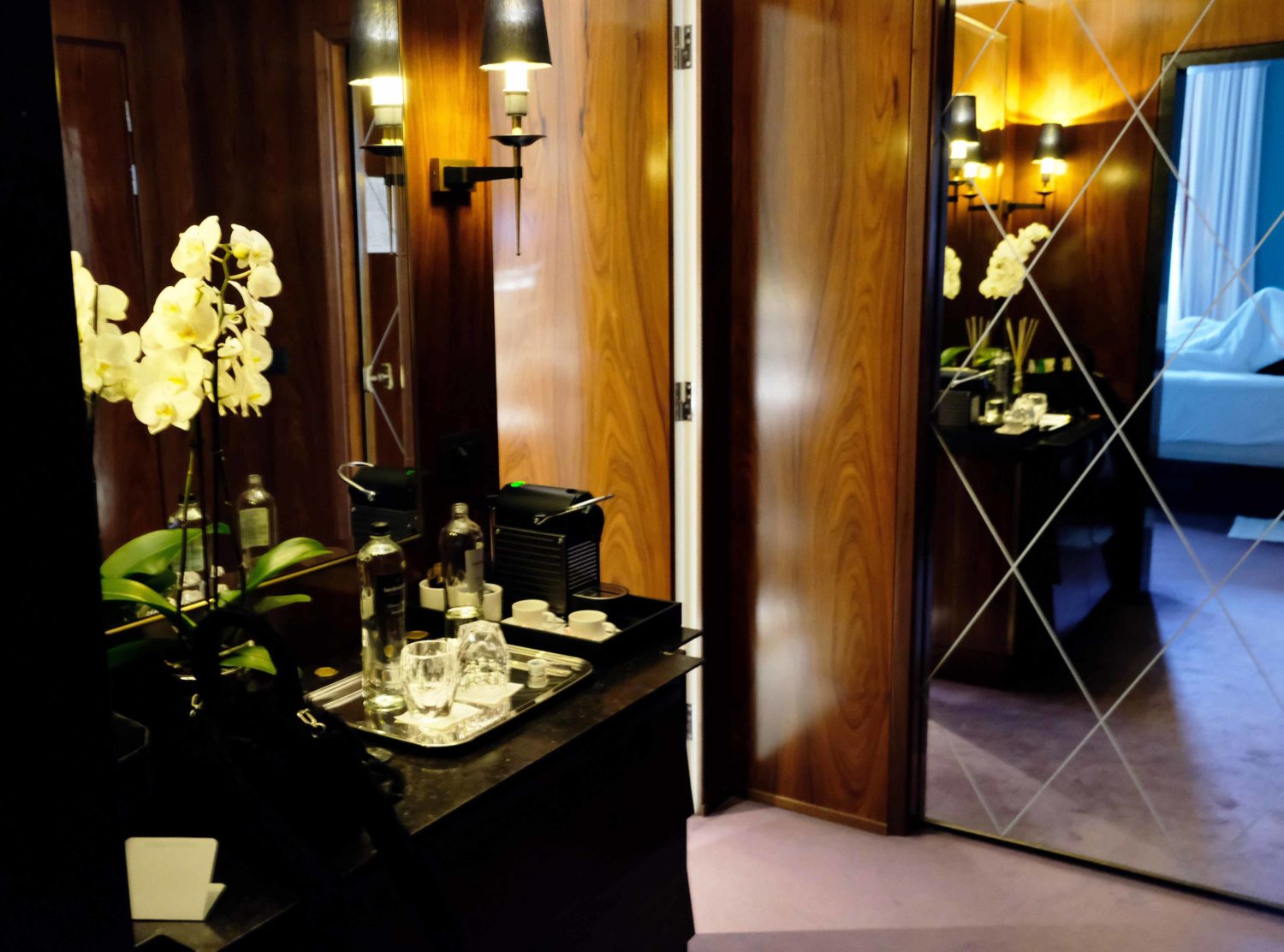 J.K. Place Roma The hallway of the suite needs a moment. Rosewood panelling, light purple rug, white orchids and mirrors to bounce the moody light — is a sophistication in 4 square meters. Behind the mirror hides a spacious closet for two over-packers 