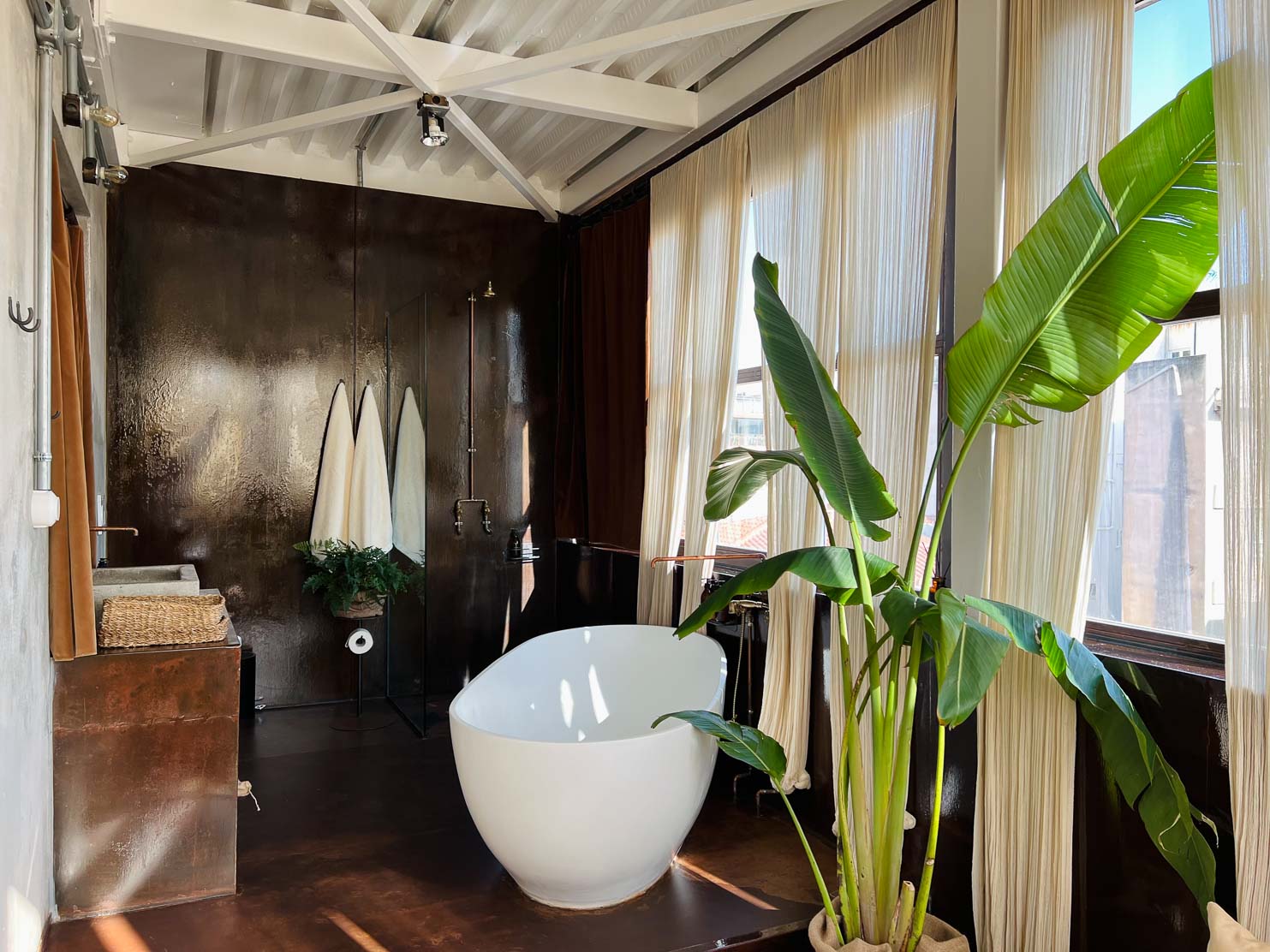 Mona The Penthouse bathroom, where the balance of comfort and sensuality extends from the bedroom, with a standalone white corian bathtub and rain shower