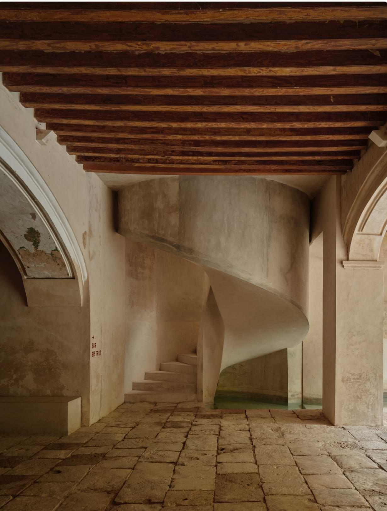 A contemporary, sculptural staircase masterfully integrated intro the hacienda original features. Photo by Fernando Marroquin.
