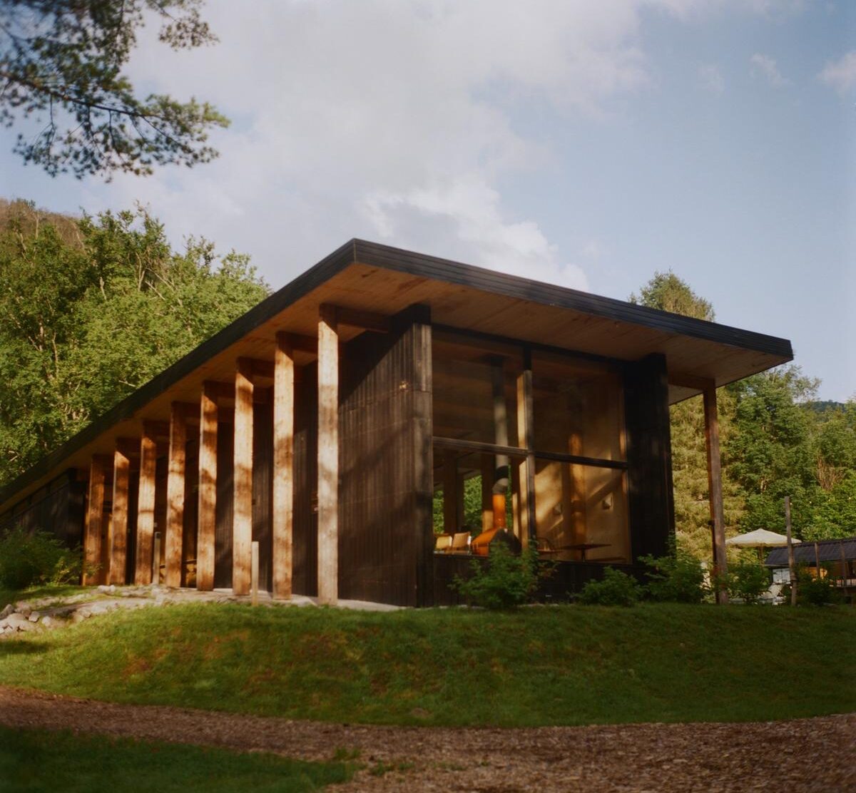 Eastwind Oliverea Valley The main pavilion, home to Dandelion Restaurant & Bar, seen in the late-day light. Deep rooflines, rhythmic timber columns and large panes of glass make it feel both monumental and completely at ease 